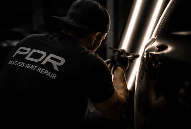 Dmitriy performing paintless dent repair with an LED light board